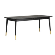 Fenwood-ruokapöytä on musta ja sen sorvatuissa jaloissa on kullanväriset metalliyksityiskohdat. Pöydän mukana on kaksi jatkopalaa, joilla pöytää voi jatkaa.