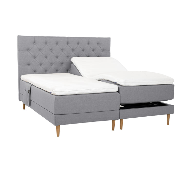 Harmaat Hilding Cross -moottorisängyt tammenvärisillä Hilding Raita -tammijaloilla, erillisillä Hilding Ergo -sijauspatjoilla ja Hilding -tarviketaskulla. Kuvan Cross -sängynpääty myydään erikseen.