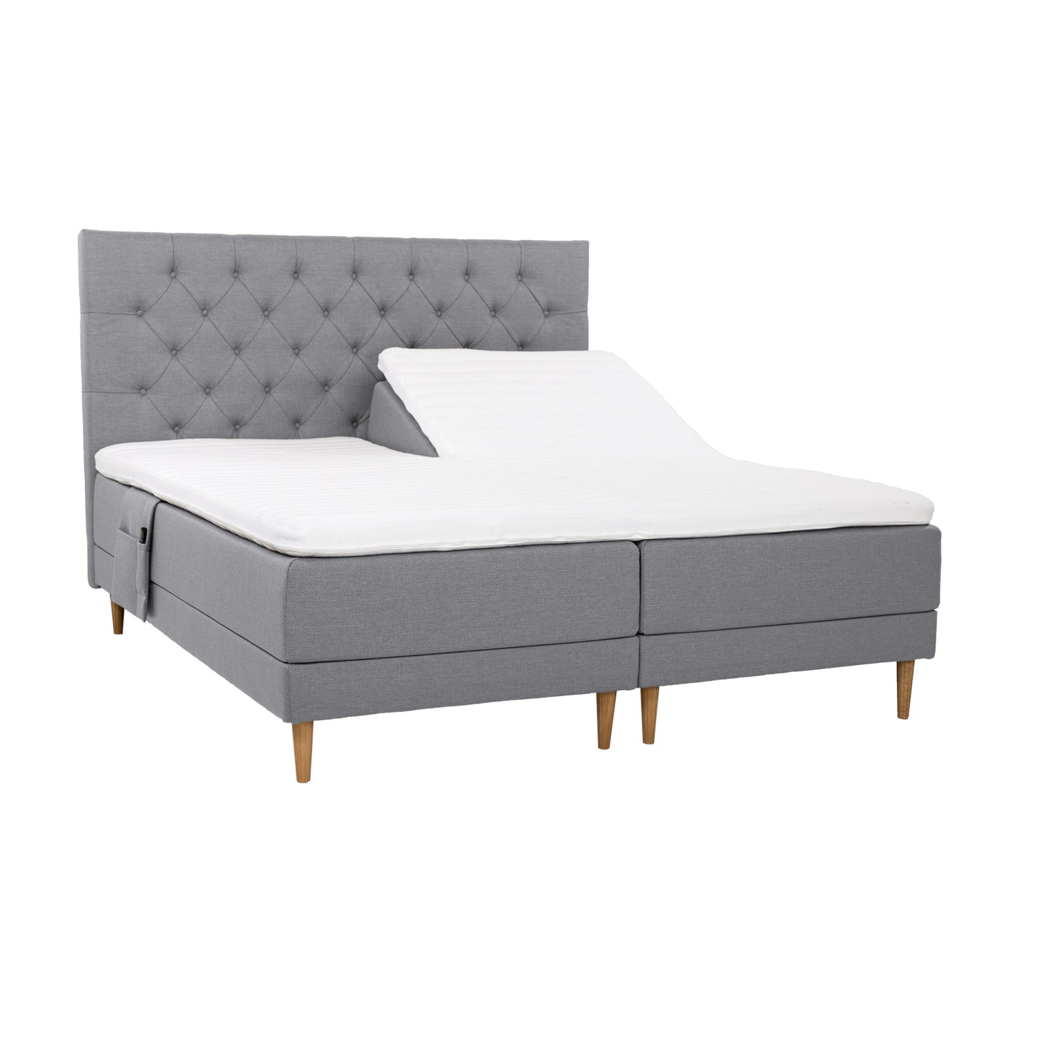 Harmaat Hilding Cross -moottorisängyt tammenvärisillä Hilding Raita -tammijaloilla, erillisillä Hilding Ergo -sijauspatjoilla ja Hilding -tarviketaskulla. Kuvan Cross -sängynpääty myydään erikseen.