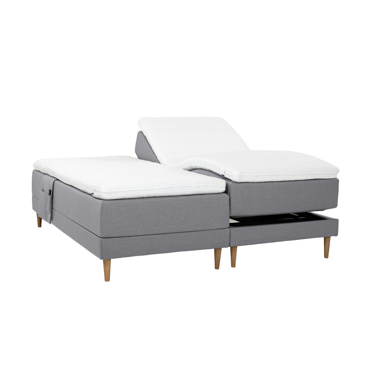 Harmaat Hilding Cross -moottorisängyt tammenvärisillä Hilding Raita -tammijaloilla, erillisillä Hilding Ergo -sijauspatjoilla ja Hilding -tarviketaskulla.