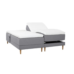 Harmaat Hilding Cross -moottorisängyt tammenvärisillä Hilding Raita -tammijaloilla, erillisillä Hilding Ergo -sijauspatjoilla ja Hilding -tarviketaskulla.