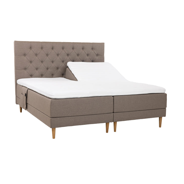 Hiekanväriset Hilding Cross -moottorisängyt tammenvärisillä Hilding Raita -tammijaloilla, erillisillä Hilding Ergo -sijauspatjoilla ja Hilding -tarviketaskulla. Kuvan Cross -sängynpääty myydään erikseen.