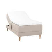 Beigenvärinen Hilding Cross -moottorisänky tammenvärisillä Hilding Raita -tammijaloilla, Hilding Ergo -sijauspatjalla ja Hilding -tarviketaskulla.