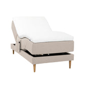 Beigenvärinen Hilding Cross -moottorisänky tammenvärisillä Hilding Raita -tammijaloilla, Hilding Ergo -sijauspatjalla ja Hilding -tarviketaskulla.