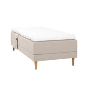 Beigenvärinen Hilding Cross -moottorisänky tammenvärisillä Hilding Raita -tammijaloilla, Hilding Ergo -sijauspatjalla ja Hilding -tarviketaskulla.