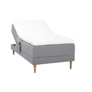 Harmaa Hilding Cross -moottorisänky tammenvärisillä Hilding Raita -tammijaloilla, Hilding Ergo -sijauspatjalla ja Hilding -tarviketaskulla.