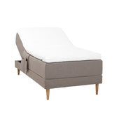 Hiekanvärinen Hilding Cross -moottorisänky tammenvärisillä Hilding Raita -tammijaloilla, Hilding Ergo -sijauspatjalla ja Hilding -tarviketaskulla.