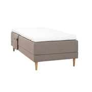 Hiekanvärinen Hilding Cross -moottorisänky tammenvärisillä Hilding Raita -tammijaloilla, Hilding Ergo -sijauspatjalla ja Hilding -tarviketaskulla.