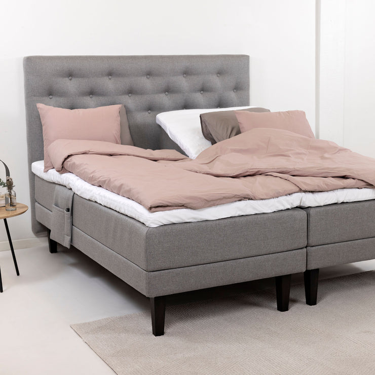 Harmaat Hilding Feel -moottorisängyt hiilenmustilla Royal -tammijaloilla. Kuvan sängyn Feel -sängynpääty ja tarviketasku & petivaatteet myydään erikseen.