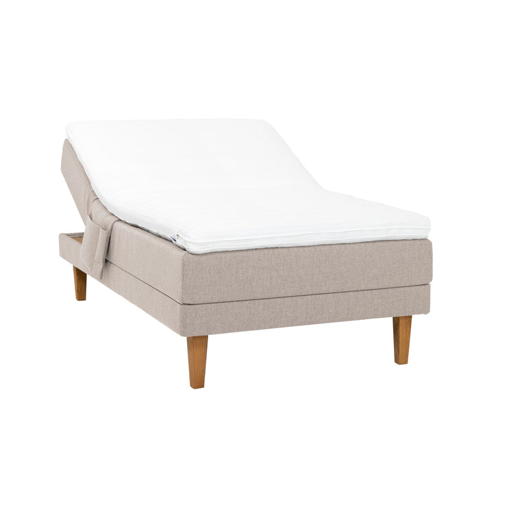 Beige Hilding Original -moottorisänky luonnonvärisillä 23 cm korkeilla Royal -tammijaloilla ja profiloidulla kimmovaahtosijauspatjalla. Kuvan tarviketasku myydään erikseen.