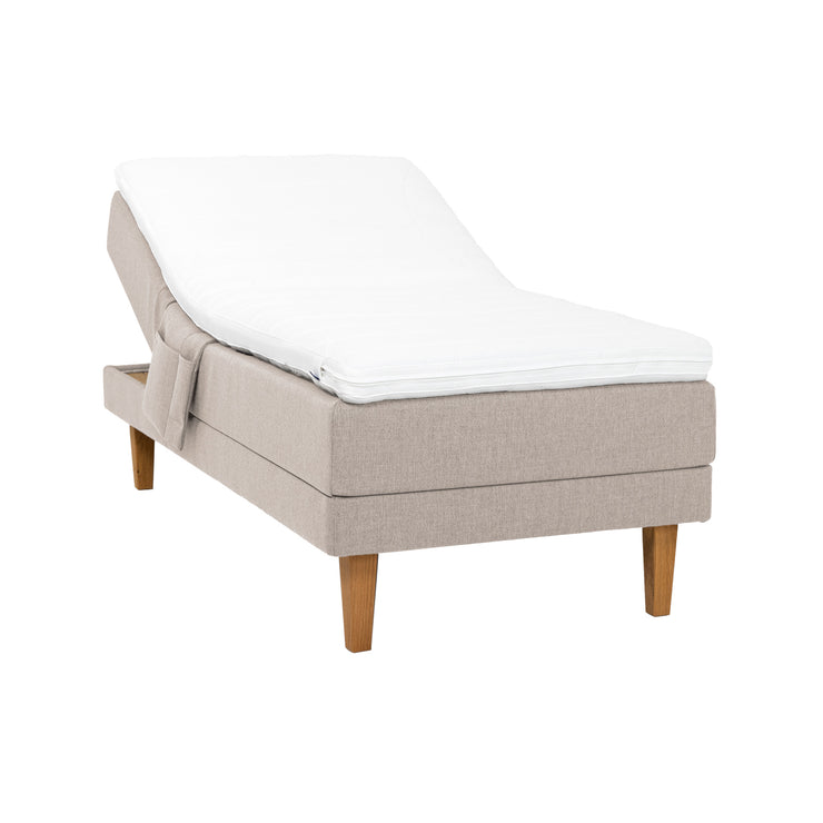 Beige Hilding Original -moottorisänky luonnonvärisillä 23 cm korkeilla Royal -tammijaloilla ja profiloidulla kimmovaahtosijauspatjalla. Kuvan tarviketasku myydään erikseen.