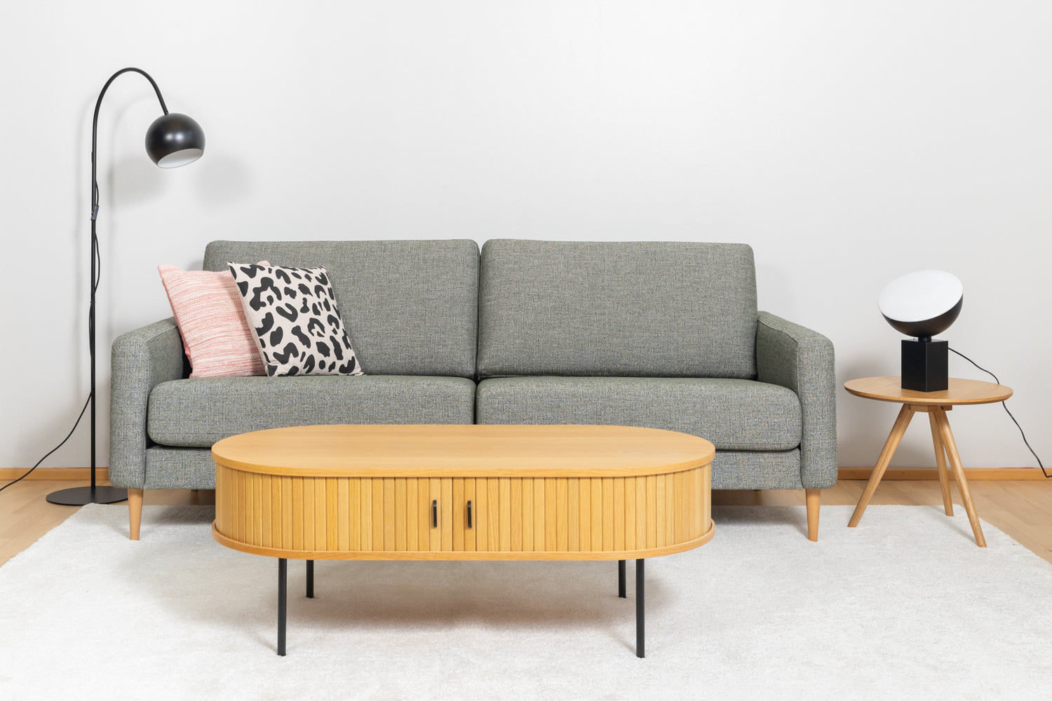 Kuvassa edessä on Nola-sohvapöytä luonnonvärisenä. Sohva on Ilona 3-istuttava ja sohvapöytänä Yumi-sarjapöytä. Mattokympin Louna-matto kokoaa sohvakaluston yhteen.