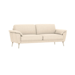 3-istuttava Ilona-sohva leveillä tyynyillä ja kermanvaalean beigellä Otaru 02 -kangasverhoilulla. Kuvan sohvassa on 20 cm leveät KN20-käsinojat ja 18 cm korkeat puiset valkoiset pyöreäkartiojalat.