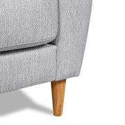 Lähikuvassa Kanerva 2 - 3h -sohvan luonnonvärinen tammijalka ja vaaleanharmaa Sparr 362 -kangasverhoilulla. Sohva on kauttaaltaan huolellisesti viimeistelty.