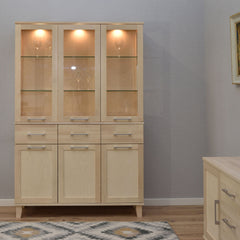 Kuvassa on valkolakattu Vuokatti-vitriini. Vitriinissä on lasikaapisto lasihyllyillä, alaosan tilava senkki kaappien peiliovilla, sekä pitkänmalliset RST-vetimet. Lasikaapin sisällä olevat valot/viinilasit eivät kuulu senkin hintaan.