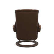 Stressless Mayfair M -lepotuoli ja rahi ruskeana: Warm Brown 87 Batick-nahkaverhoilulla ja pähkinä petsatulla -Classic-puujalustalla.