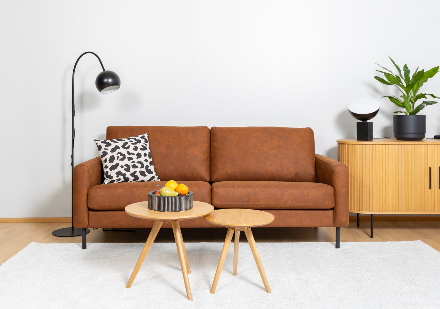 Kuvassa on musta Pod-poytavalaisin Nola-senkin päällä oikealla ja vasemmalla Round Single-lattiavalaisin. Lisäksi kuvassa on Mila 3-istuttava sohva,
valkoinen Louna-matto, Yumi-sarjapoydät, sekä Rita-koristetyyny.