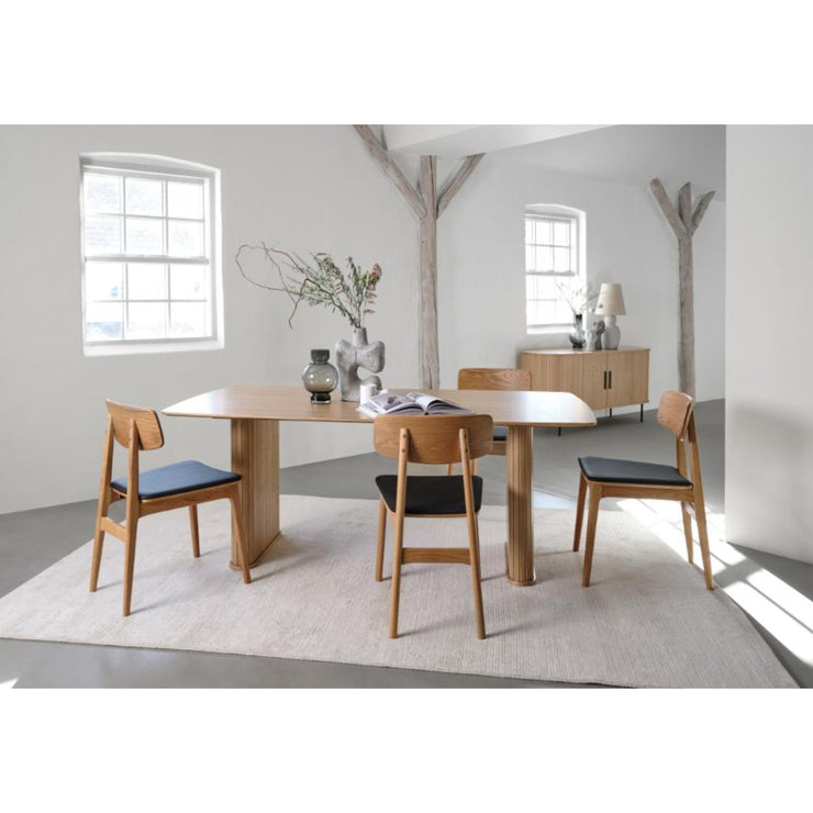 Kuvassa on Nola-ruokapöytä, joka on tyylikäs pöytä kahdella jalalla. Paneloidut, jykevät jalat tuovat ilmettä sisustukseen. Kuvan pöytään on yhdistetty väljästi neljä tuolia ja se on hyvin yhdistettävissä yhteensä kuuteen tuoliin.