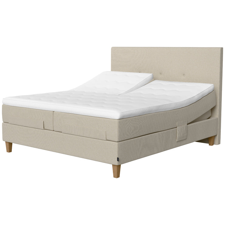 Jensen Onyx -säätösängyn luonnonvaalea Natural 292 verhoiluväri ja nelikulmaiset 23 cm korkeat luonnonväriset tammijalat. Erilliset TempSmart -sijauspatjat ja jalat sisältyvät pakettiin. Kuvassa on myös erikseen myytävät split-mallinen ylhäältä halkaistu petauspatja, yhtenäinen verhoilu (4-jalalla) ja sängynpääty.