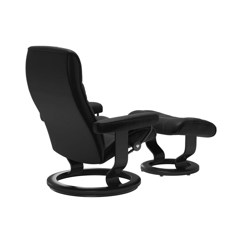 Stressless Opal M -lepotuoli ja rahi mustana: Black 19 Batick-nahkaverhoilulla ja musta petsatulla -Classic-puujalustalla.