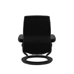 Stressless Opal M -lepotuoli ja rahi mustana: Black 19 Batick-nahkaverhoilulla ja musta petsatulla -Classic-puujalustalla.