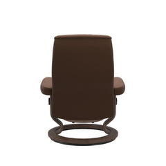 Stressless Opal M -lepotuoli ja rahi ruskeana: Warm Brown 87 Batick-nahkaverhoilulla ja Walnut 06 -Classic-puujalustalla.