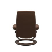 Stressless Opal M -lepotuoli ja rahi ruskeana: Warm Brown 87 Batick-nahkaverhoilulla ja pähkinä petsatulla -Classic-puujalustalla.