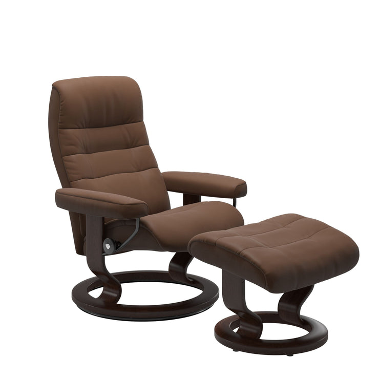 Stressless Opal M -lepotuoli ja rahi ruskeana: Warm Brown 87 Batick-nahkaverhoilulla ja ruskea petsatulla -Classic-puujalustalla.