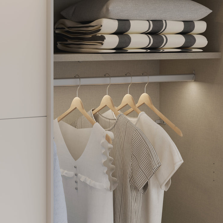 Kuvassa on mattavalkoinen Kira-liukuovikomero, toinen liukuovi avoinna. Kaapin sisus on väriltään harmaata kangasjäljitelmää.