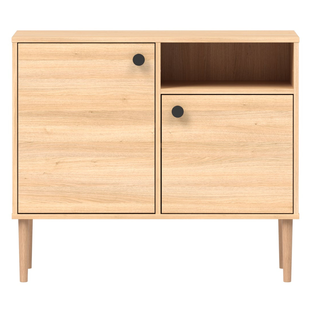 Tammenvärinen Stemma-lipastokaappi luonnonvärisillä tammijaloilla ja mustilla nuppivetimillä.