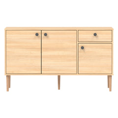 Tammenvärinen Stemma-senkki tammisilla jaloilla. Kalusteessa on mustat nuppivetimet.