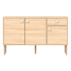 Tammenvärinen Stemma-senkki tammisilla jaloilla. Kalusteessa on valkoiset nuppivetimet.