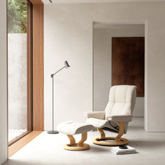 Stressless Mayfair -lepotuoli ja rahi valkoisena: Milky White 05 Batick-nahkaverhoilulla ja erikseen myytävällä tammipetsatulla -Classic-puujalustalla.