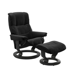 Stressless Mayfair M -lepotuoli ja rahi mustana: Black 19 Batick-nahkaverhoilulla ja harmaa petsatulla -Classic-puujalustalla.