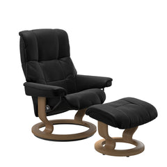 Stressless Mayfair M -lepotuoli ja rahi mustana: Black 19 Batick-nahkaverhoilulla ja tammi petsatulla -Classic-puujalustalla.