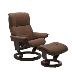 Stressless Mayfair M -lepotuoli ja rahi ruskeana: Warm Brown 87 Batick-nahkaverhoilulla ja ruskea petsatulla -Classic-puujalustalla.
