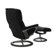 Stressless Mayfair M -lepotuoli ja rahi mustana: Black 19 Paloma-nahkaverhoilulla ja harmaa petsi 08 pyökki/kiiltävä alumiini Alu 40 -Signature-yhdistelmäjalustalla.