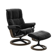 Stressless Mayfair M -lepotuoli ja rahi mustana: Black 19 Paloma-nahkaverhoilulla ja savutammi 13 petsattu pyökki/mattamusta 40 metalli -Signature-yhdistelmäjalustalla.