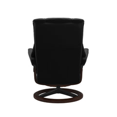 Stressless Mayfair M -lepotuoli ja rahi mustana: Black 19 Paloma-nahkaverhoilulla ja ruskea petsi 03/mattamusta 45 metalli -Signature-yhdistelmäjalustalla.