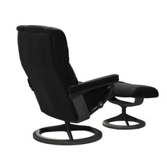 Stressless Mayfair M -lepotuoli ja rahi mustana: Black 19 Paloma-nahkaverhoilulla ja harmaa petsattu pyökki 08/mattamusta 45 metalli -Signature-yhdistelmäjalustalla.