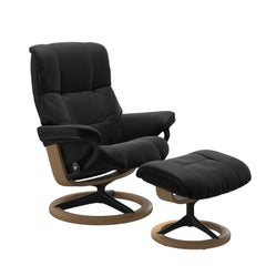 Stressless Mayfair M -lepotuoli ja rahi mustana: Black 19 Paloma-nahkaverhoilulla ja tammi petsi 04/mattamusta 45 metalli -Signature-yhdistelmäjalustalla.