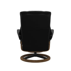 Stressless Mayfair M -lepotuoli ja rahi mustana: Black 19 Paloma-nahkaverhoilulla ja teak petsi 02 pyökki/mattamusta 45 metalli -Signature-yhdistelmäjalustalla.