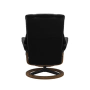 Stressless Mayfair M -lepotuoli ja rahi mustana: Black 19 Paloma-nahkaverhoilulla ja teak petsi 02 pyökki/mattamusta 45 metalli -Signature-yhdistelmäjalustalla.