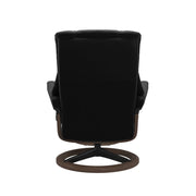 Stressless Mayfair M -lepotuoli ja rahi mustana: Black 19 Paloma-nahkaverhoilulla ja pähkinä petsi 06 pyökki/mattamusta 45 metalli -Signature-yhdistelmäjalustalla.