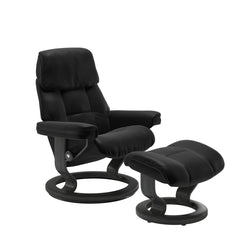 Stressless Ruby M -lepotuoli ja rahi mustana: Black 19 Batick-nahkaverhoilulla ja harmaa petsatulla -Classic-puujalustalla.