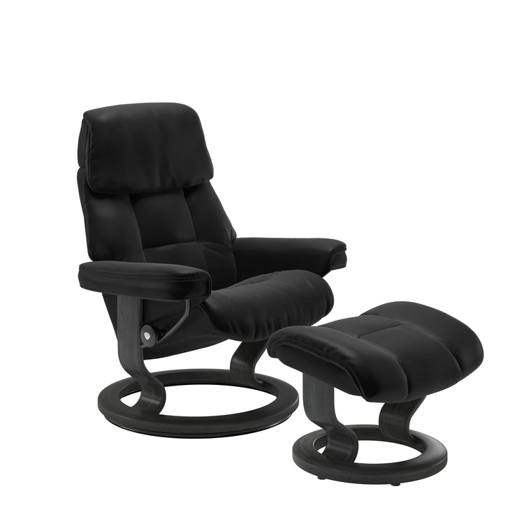Stressless Ruby M -lepotuoli ja rahi mustana: Black 19 Batick-nahkaverhoilulla ja harmaa petsatulla -Classic-puujalustalla.