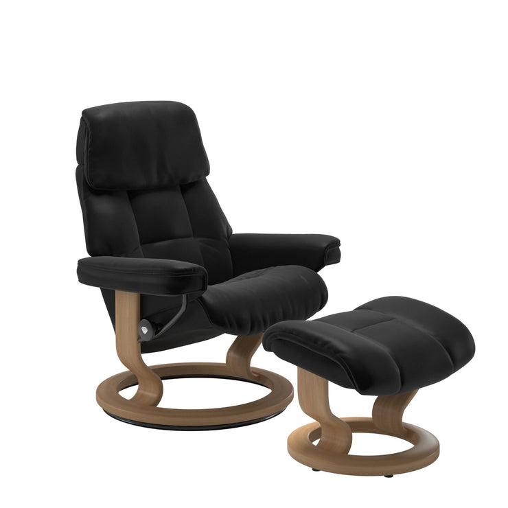 Stressless Ruby M -lepotuoli ja rahi mustana: Black 19 Batick-nahkaverhoilulla ja tammi petsatulla -Classic-puujalustalla.