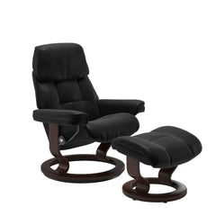 Stressless Ruby M -lepotuoli ja rahi mustana: Black 19 Batick-nahkaverhoilulla ja ruskea petsatulla -Classic-puujalustalla.