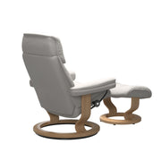 Stressless Ruby M -lepotuoli ja rahi valkoisena: Milky White 05 Batick-nahkaverhoilulla ja tammi petsatulla -Classic-puujalustalla.