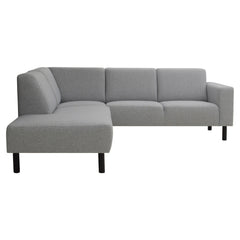 Divaallinen Tessa-avokulmasohva harmaalla Land 90 -kankaalla, 20 cm leveällä käsinojalla ja mustilla 18 cm pyöreäkartiopuujaloilla.